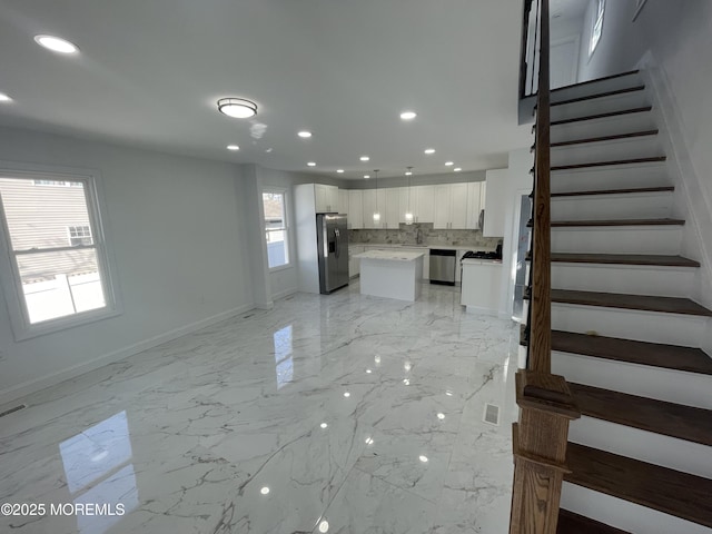 unfurnished living room with stairs, marble finish floor, baseboards, and recessed lighting