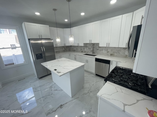 kitchen with light stone counters, appliances with stainless steel finishes, a center island, a sink, and backsplash