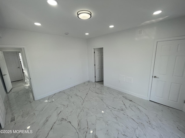 empty room featuring marble finish floor, baseboards, and recessed lighting