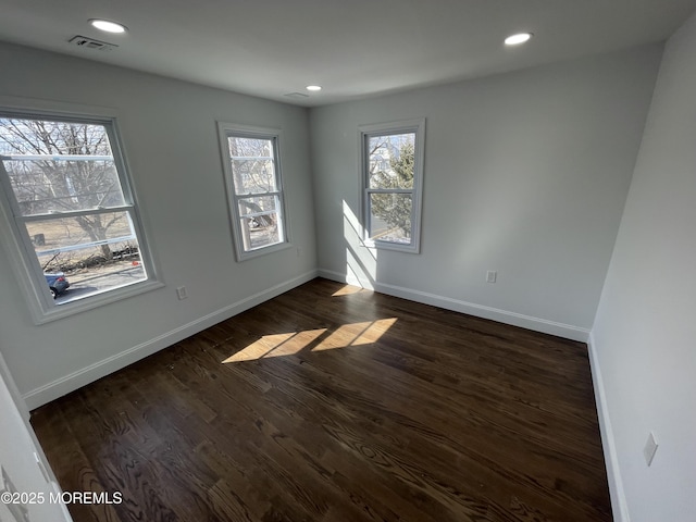 empty room with dark wood-type flooring, recessed lighting, visible vents, and baseboards