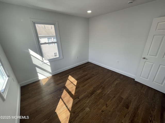 empty room with dark wood-type flooring, recessed lighting, and baseboards