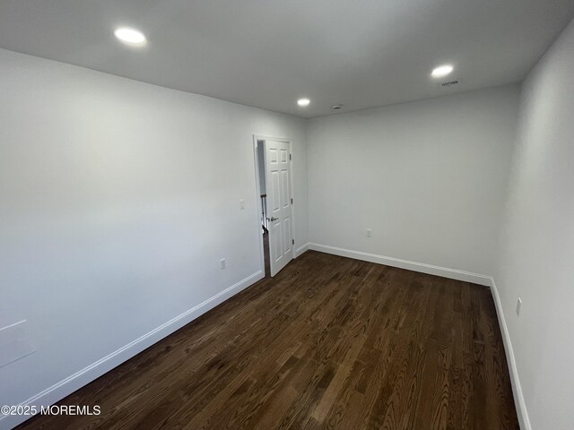 spare room with dark wood-type flooring, recessed lighting, visible vents, and baseboards