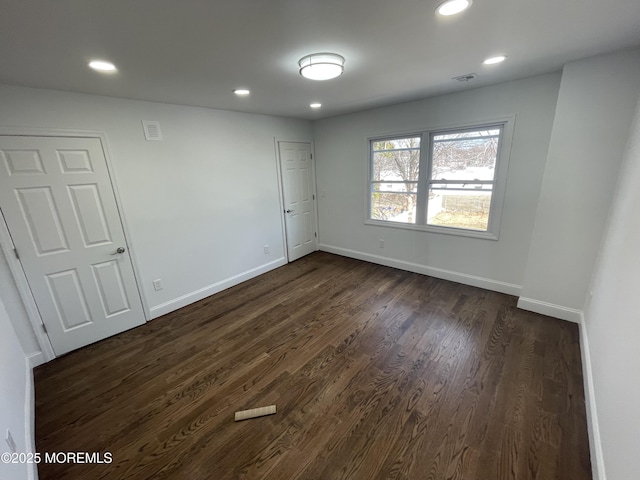 spare room featuring dark wood-style flooring, recessed lighting, and baseboards