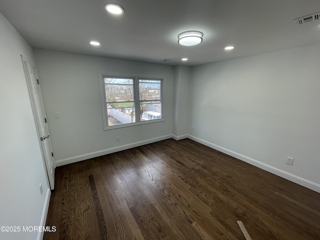 spare room featuring recessed lighting, dark wood-style flooring, visible vents, and baseboards