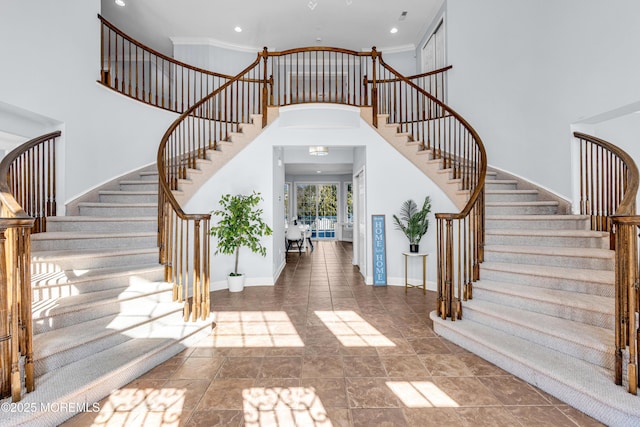 foyer entrance with stairs, ornamental molding, a towering ceiling, and baseboards