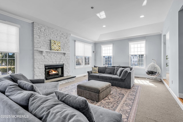 living room featuring baseboards, a stone fireplace, carpet flooring, and crown molding