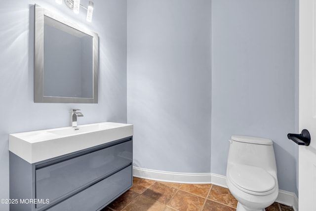 bathroom with toilet, vanity, and baseboards