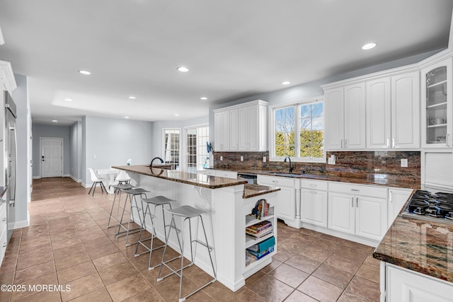 kitchen featuring dark stone counters, white cabinetry, and a breakfast bar area