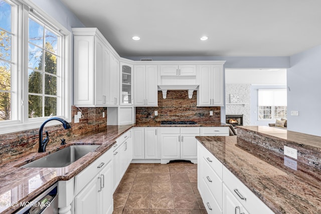 kitchen with gas stovetop, backsplash, glass insert cabinets, white cabinetry, and a sink