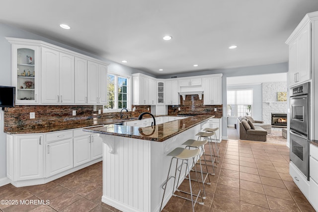 kitchen featuring tasteful backsplash, glass insert cabinets, a wealth of natural light, and a kitchen breakfast bar