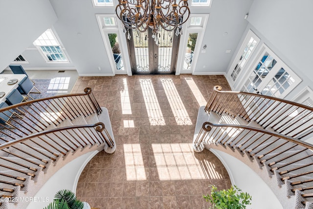 entryway featuring a high ceiling, baseboards, french doors, stairway, and an inviting chandelier