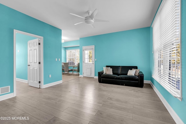 living room featuring visible vents, ceiling fan, baseboards, and wood finished floors