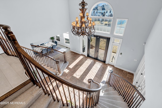 tiled foyer entrance featuring french doors, a high ceiling, stairway, and a notable chandelier