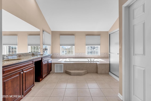 kitchen featuring light stone counters, visible vents, light tile patterned flooring, vaulted ceiling, and a sink