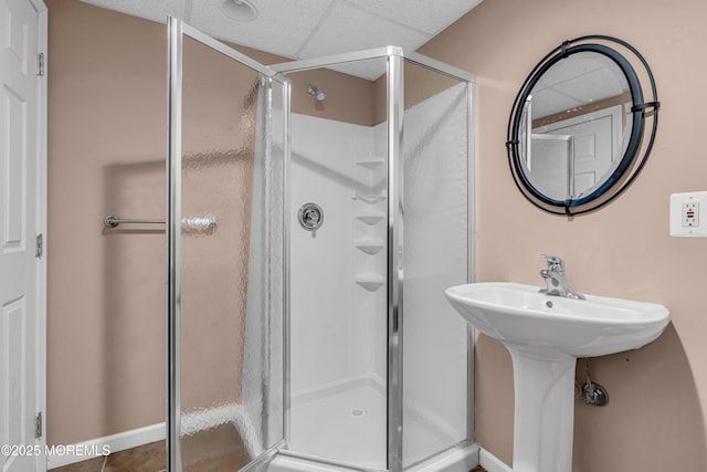 bathroom with a drop ceiling and a shower stall