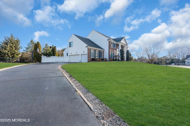 view of front of house with aphalt driveway, brick siding, an attached garage, a front yard, and fence