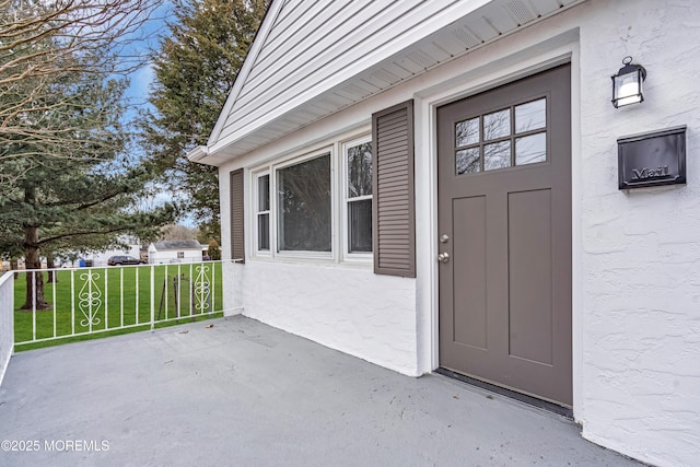 property entrance with a lawn and stucco siding