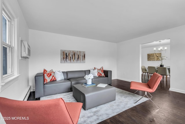 living area featuring a wall unit AC, an inviting chandelier, a baseboard heating unit, wood finished floors, and baseboards