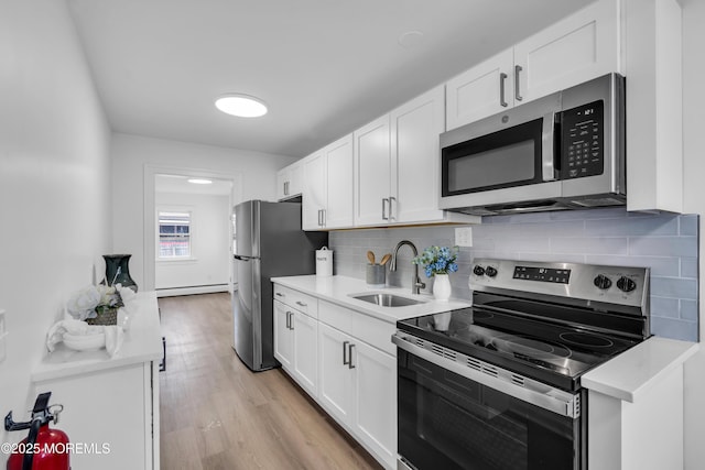 kitchen with light countertops, appliances with stainless steel finishes, a sink, and white cabinets