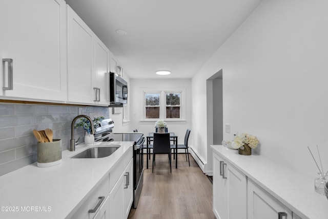 kitchen featuring a sink, stainless steel appliances, light countertops, and white cabinetry