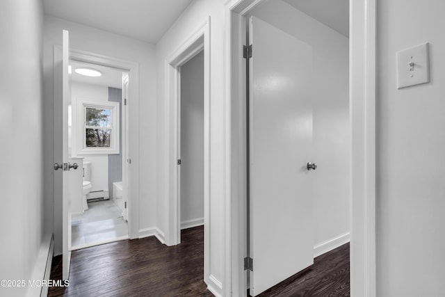 hallway featuring dark wood finished floors and baseboards