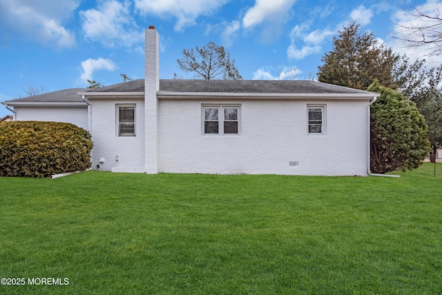 back of property featuring crawl space, a lawn, a chimney, and stucco siding