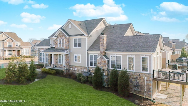 view of front facade featuring a residential view, stone siding, metal roof, and a front lawn