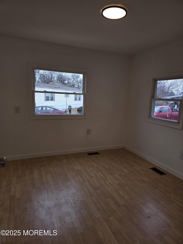 empty room with visible vents, baseboards, and wood finished floors