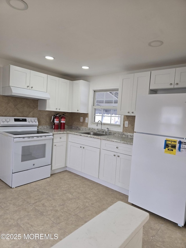 kitchen featuring white appliances, tasteful backsplash, white cabinets, under cabinet range hood, and a sink