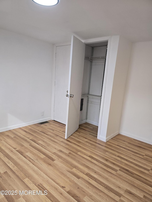 unfurnished bedroom with light wood finished floors, a closet, and baseboards