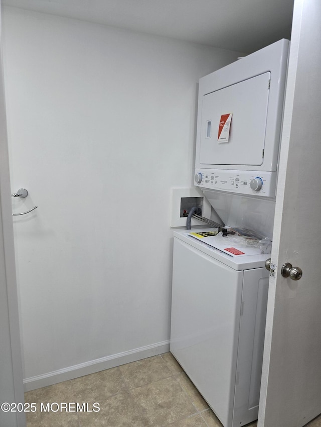 washroom with baseboards and stacked washer / drying machine