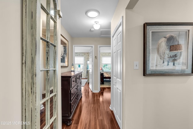 hallway featuring dark wood-type flooring and baseboards