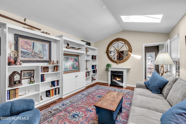 living room with lofted ceiling with skylight, a lit fireplace, baseboards, and wood finished floors