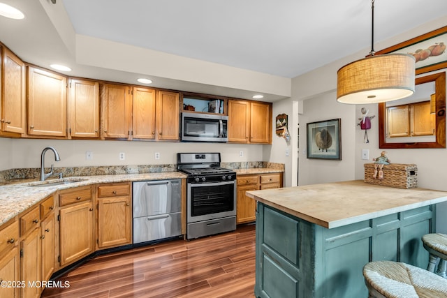 kitchen with dark wood-style flooring, decorative light fixtures, stainless steel appliances, a sink, and a peninsula