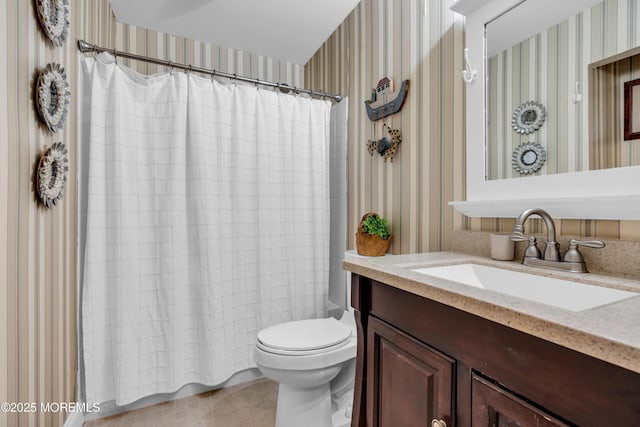 bathroom featuring toilet, vanity, and wallpapered walls