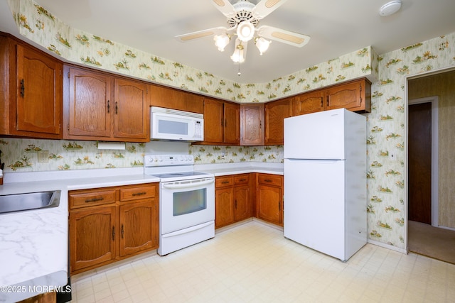 kitchen with brown cabinetry, white appliances, light countertops, and wallpapered walls