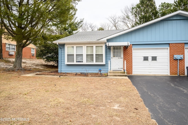 ranch-style home with aphalt driveway, roof with shingles, an attached garage, and brick siding