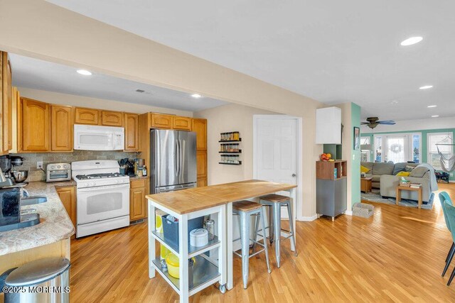 kitchen with white appliances, tasteful backsplash, open floor plan, light wood-style floors, and recessed lighting