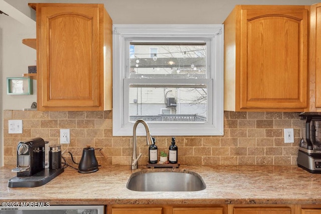 kitchen with dishwasher, a sink, decorative backsplash, and light stone countertops