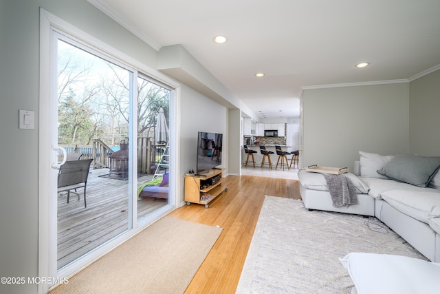 living room featuring light wood-type flooring, crown molding, and recessed lighting