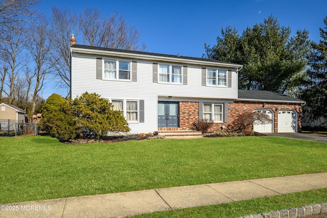 view of front of house with an attached garage, brick siding, driveway, a front lawn, and a chimney