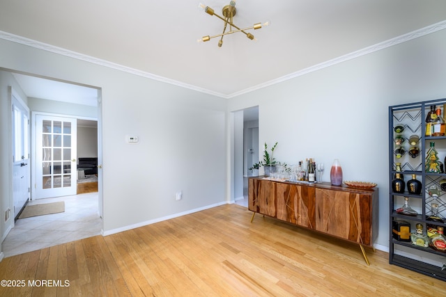 interior space with ornamental molding, light wood-type flooring, an inviting chandelier, and baseboards