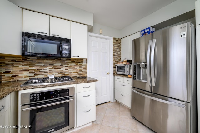 kitchen featuring light tile patterned floors, a toaster, white cabinets, stainless steel appliances, and backsplash