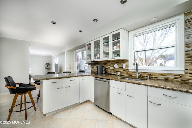 kitchen with tasteful backsplash, a sink, a peninsula, and stainless steel dishwasher