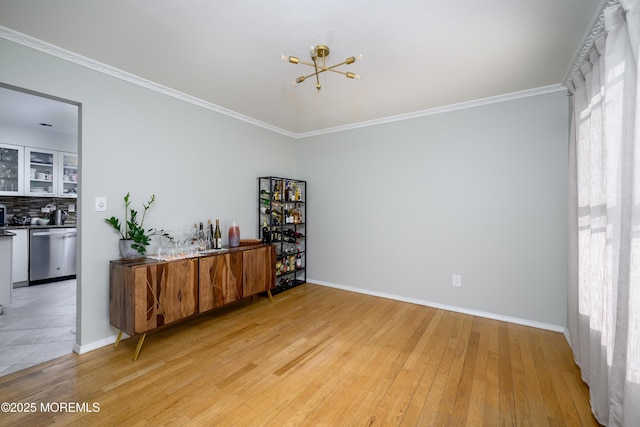 interior space featuring light wood-type flooring, an inviting chandelier, baseboards, and ornamental molding