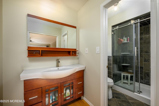 bathroom featuring a stall shower, baseboards, toilet, tile patterned flooring, and vanity