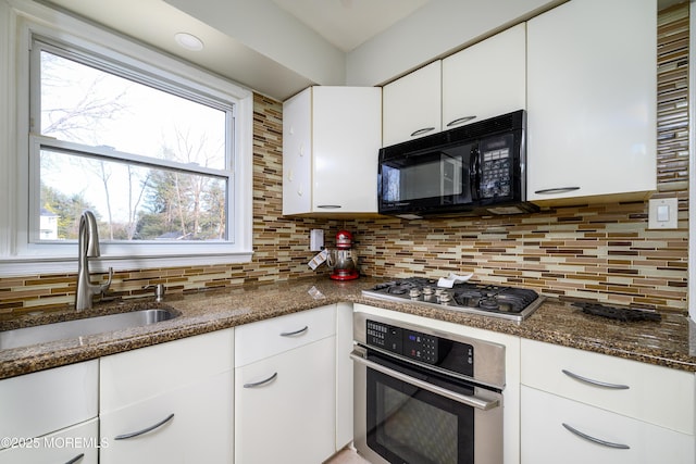 kitchen featuring appliances with stainless steel finishes, backsplash, a sink, and white cabinetry