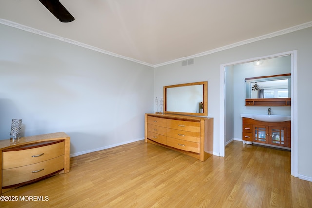 unfurnished bedroom featuring light wood-style flooring, a sink, visible vents, baseboards, and crown molding