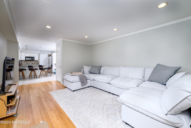 living area with light wood-style floors, recessed lighting, and crown molding