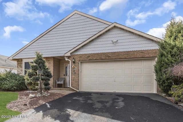 ranch-style home featuring an attached garage and aphalt driveway